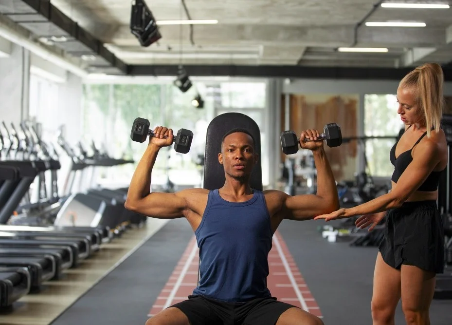 Coach en formation encadrant un élève en musculation dans une salle de sport, pendant la partie pratique du CQP Instructeur Fitness à distance, organisée chaque week-end à Paris.